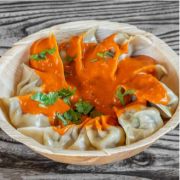 Steamed Chicken Momo Simmered in Homemade Butter Masala Sauce